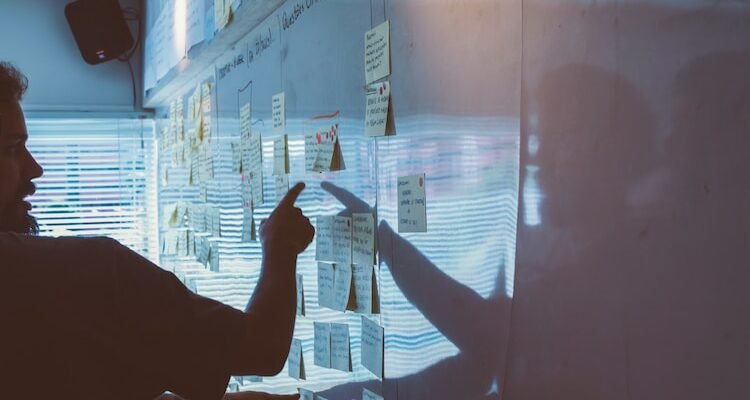 person pointing white paper on wall